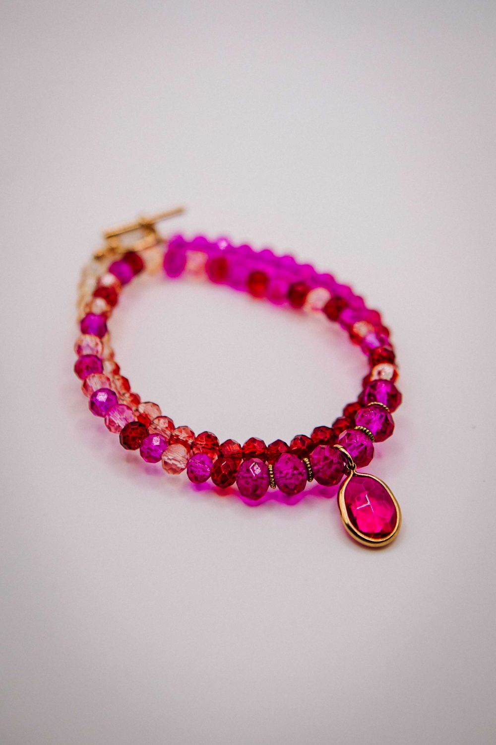 Beaded bracelet with pink and red beads on a light gray background