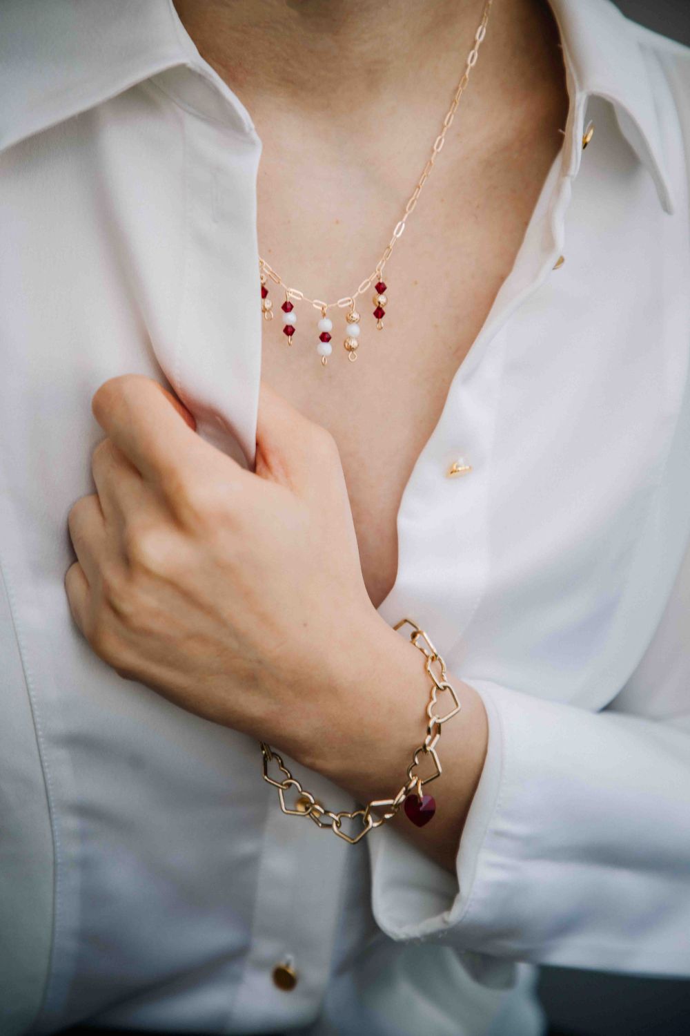 Gold necklace and bracelet on a person wearing a white shirt