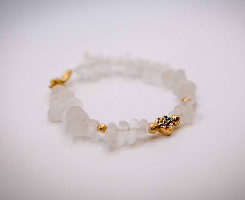White beaded bracelet with gold accents on a light gray background