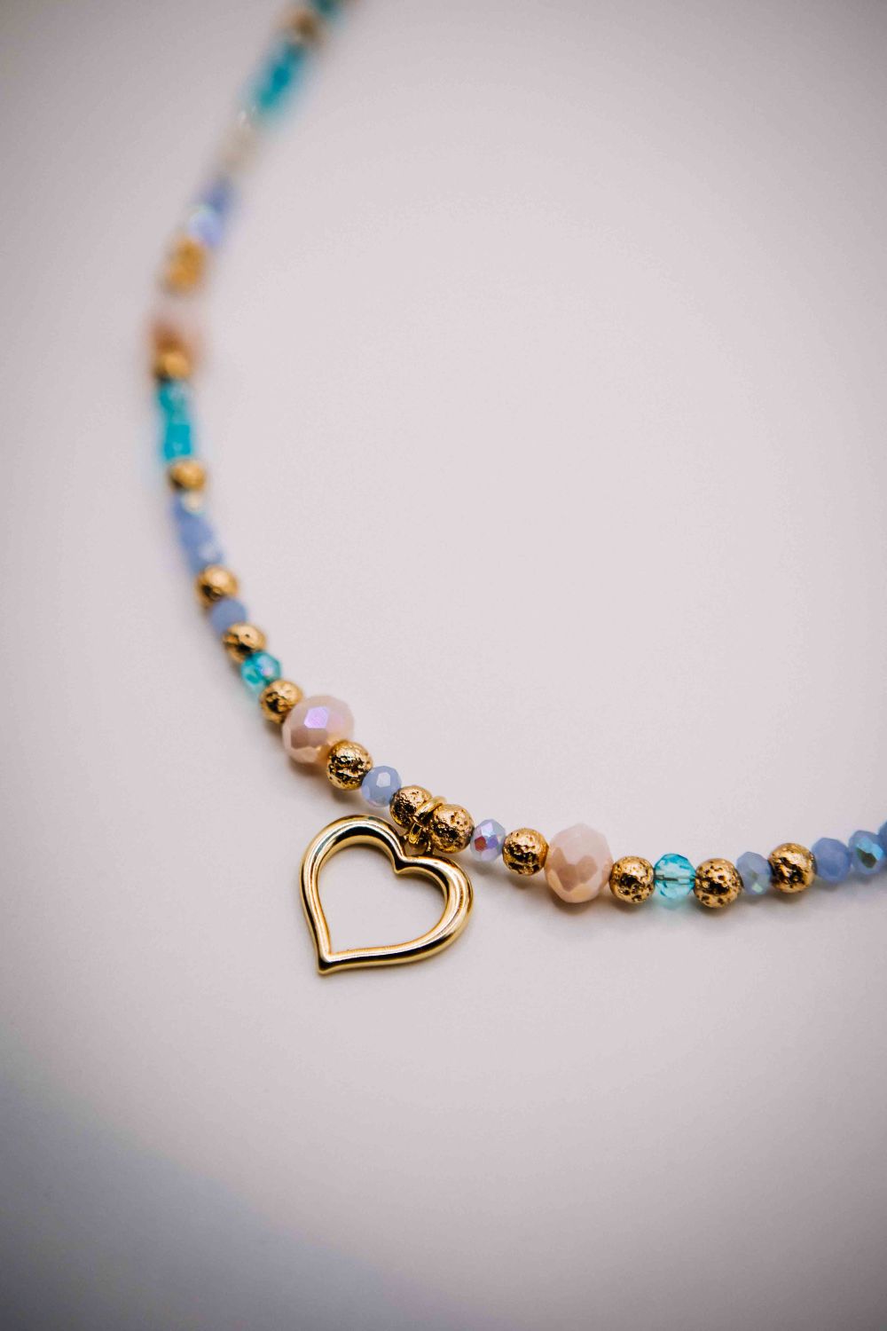 Necklace with heart charm and multicolored beads on a light background