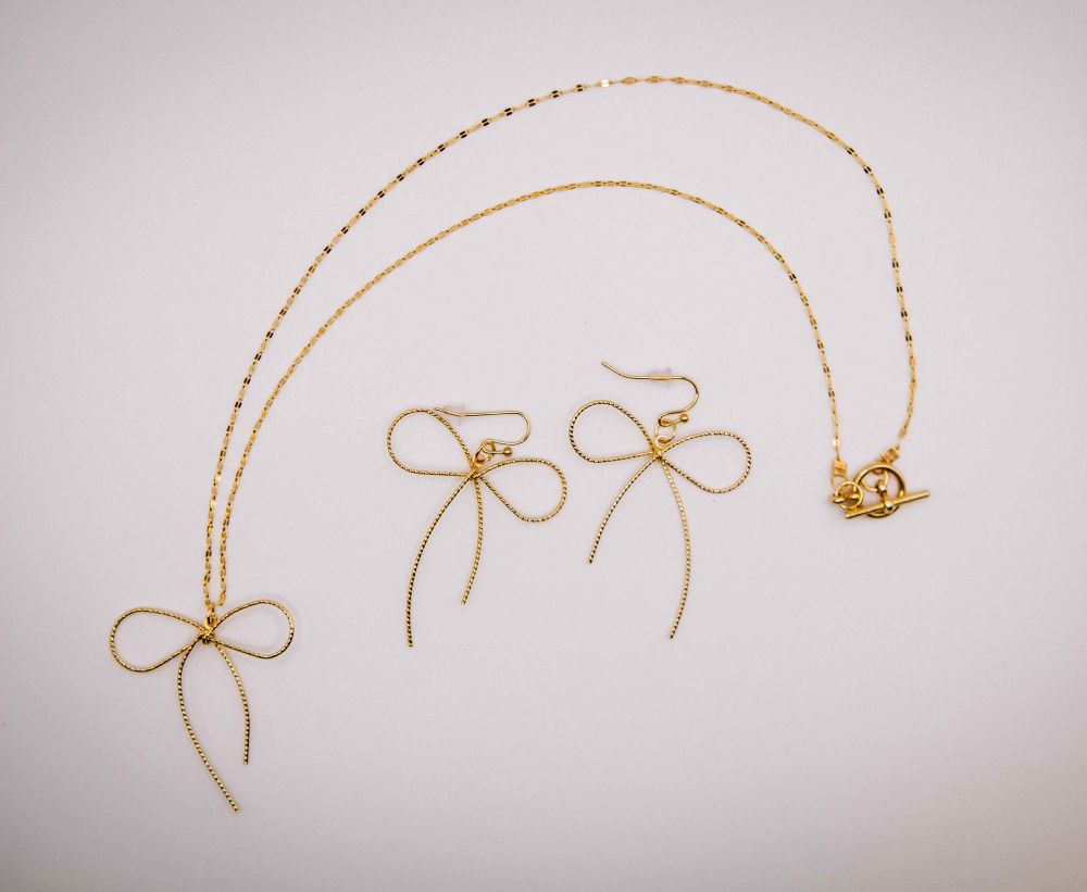 Gold necklace and earrings on a light gray background