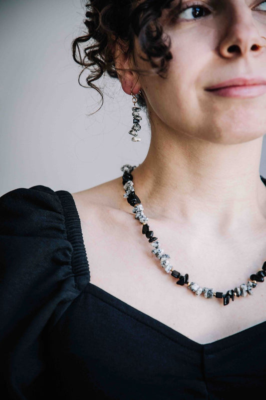 Woman wearing a black and white necklace with a plain background