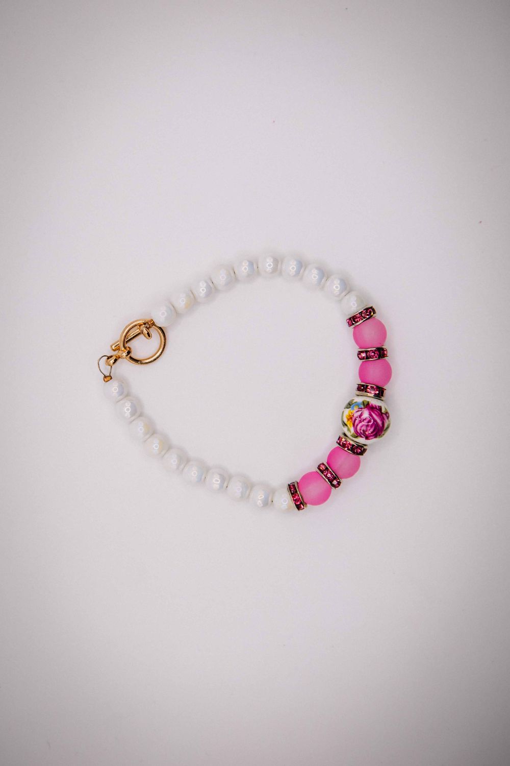 Bracelet with pink beads and a gold clasp on a white background