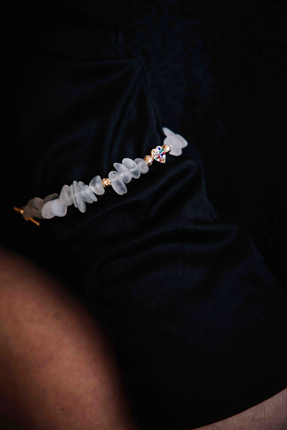 Clear crystal bracelet with gold accents on a dark fabric background