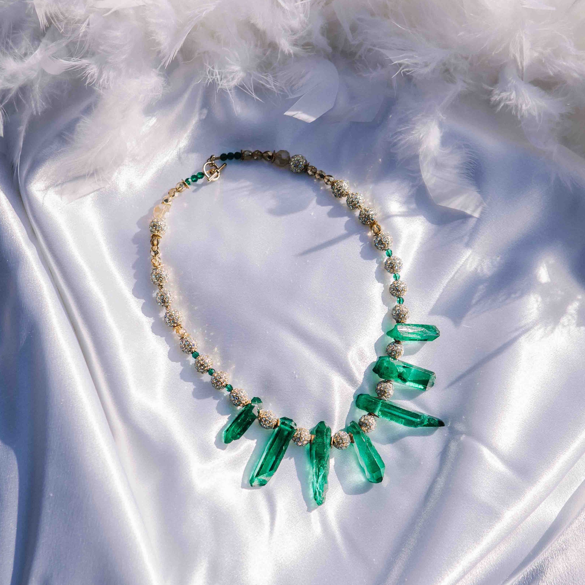 Necklace with emerald spikes on a white fabric background