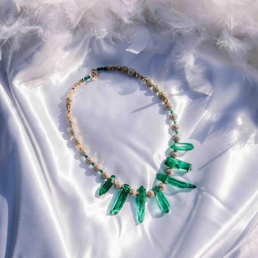 Necklace with emerald spikes on a white fabric background